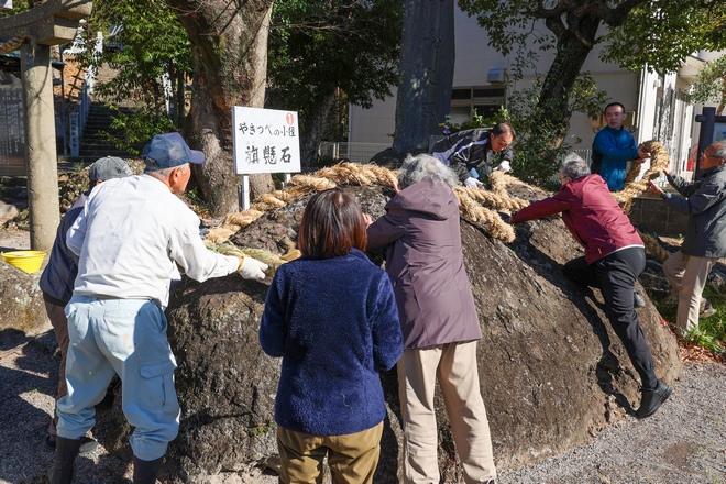 旗掛石に皆で新しいしめ縄をかける様子